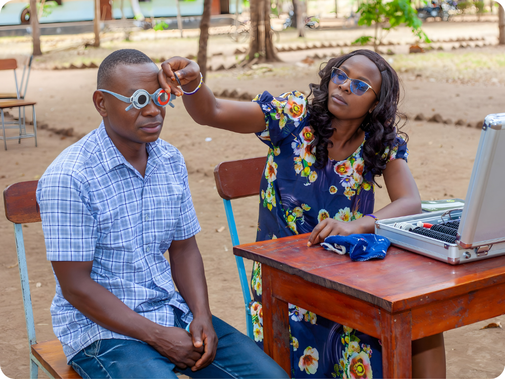 Leeraar krijgt oogscreening op het schoolplein in Tanzania.