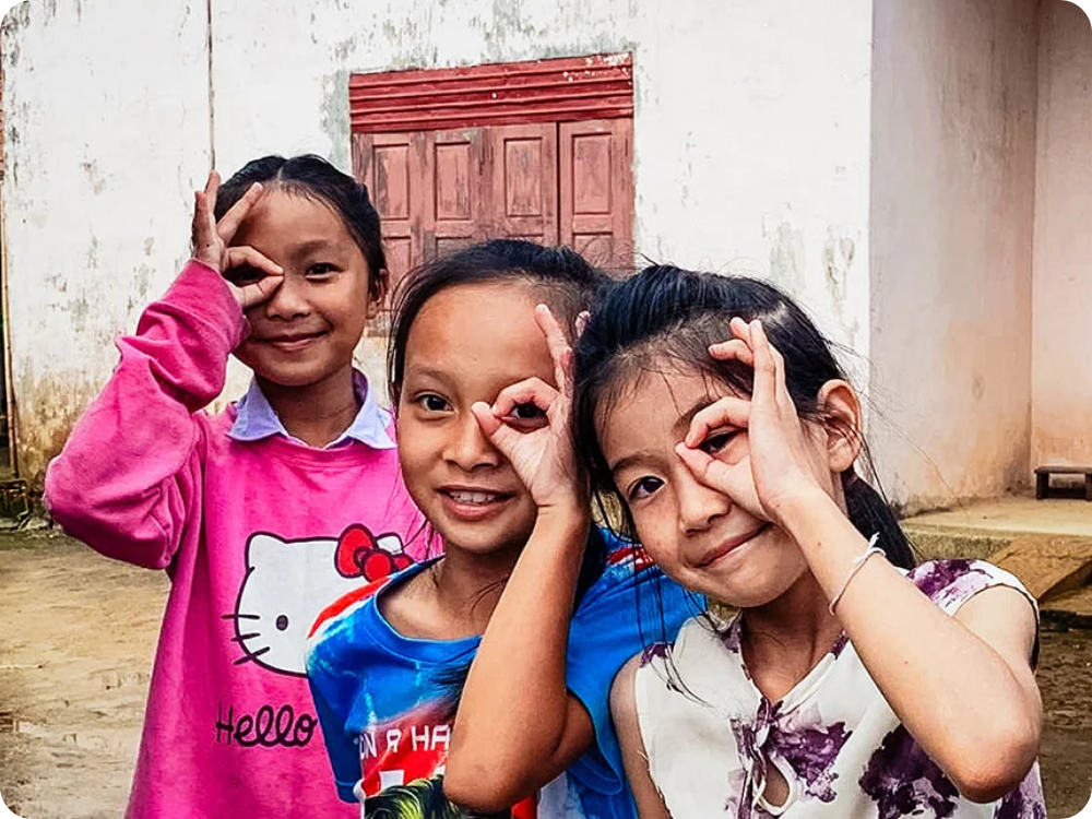 Drie meisjes in Vietnam doen het oogteken met hun hand