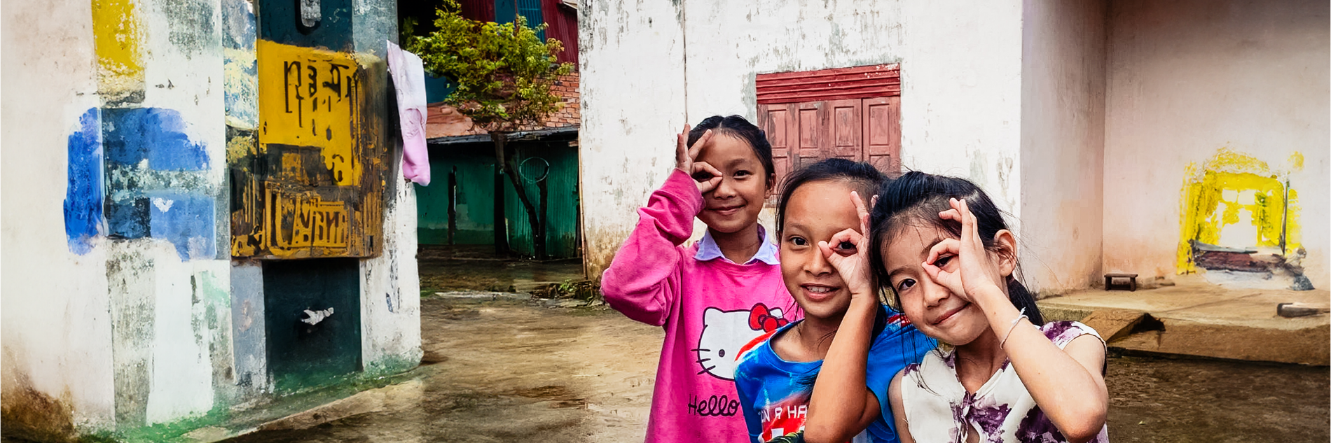 Drie meisjes in Vietnam doen het oogteken met hun hand